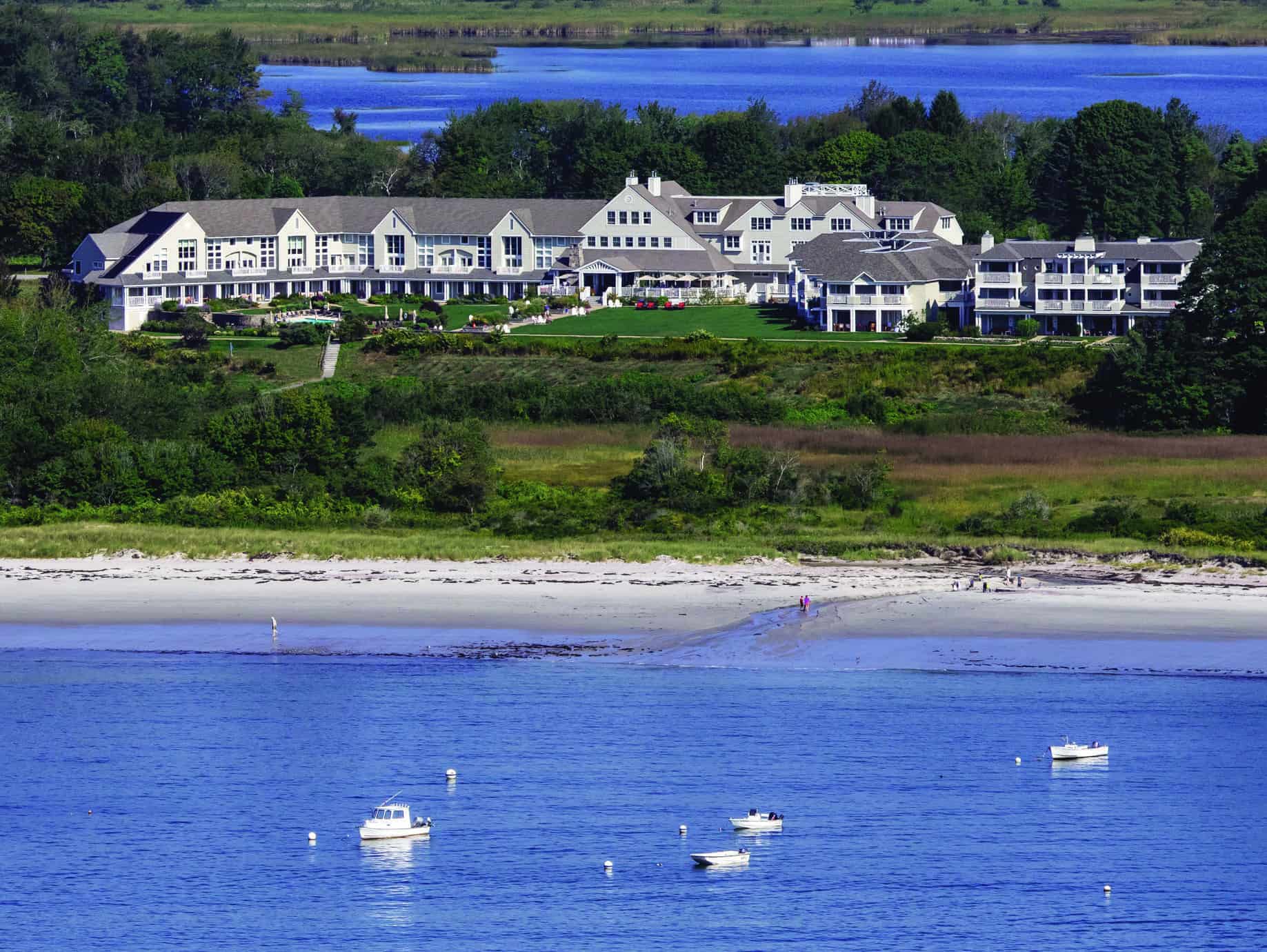 A very large white Portland Maine inn faces the ocean under a sunny sky.