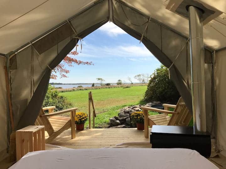 View of the ocean and green space through the opening of a tent.