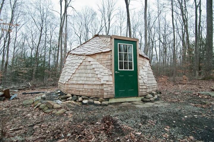 Wooden yurt in the woods with a green door.