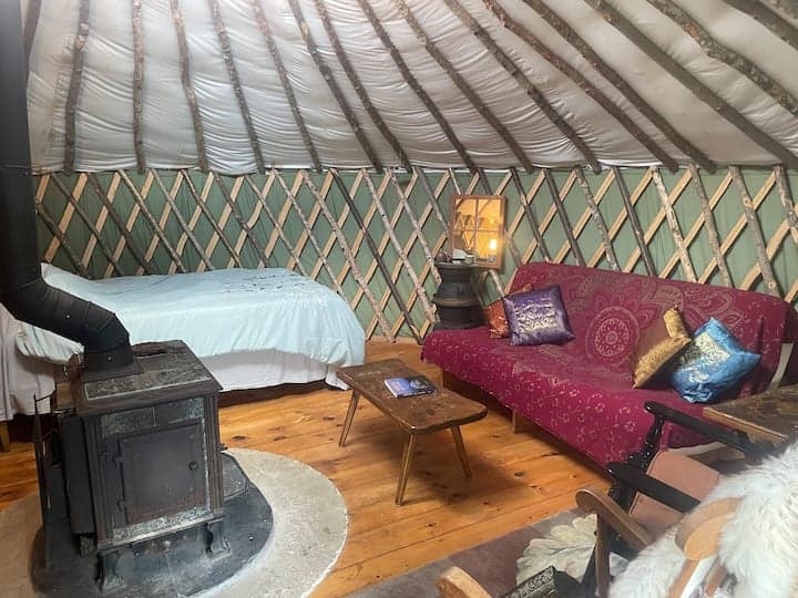 Interior of a yurt with a red couch and bed.