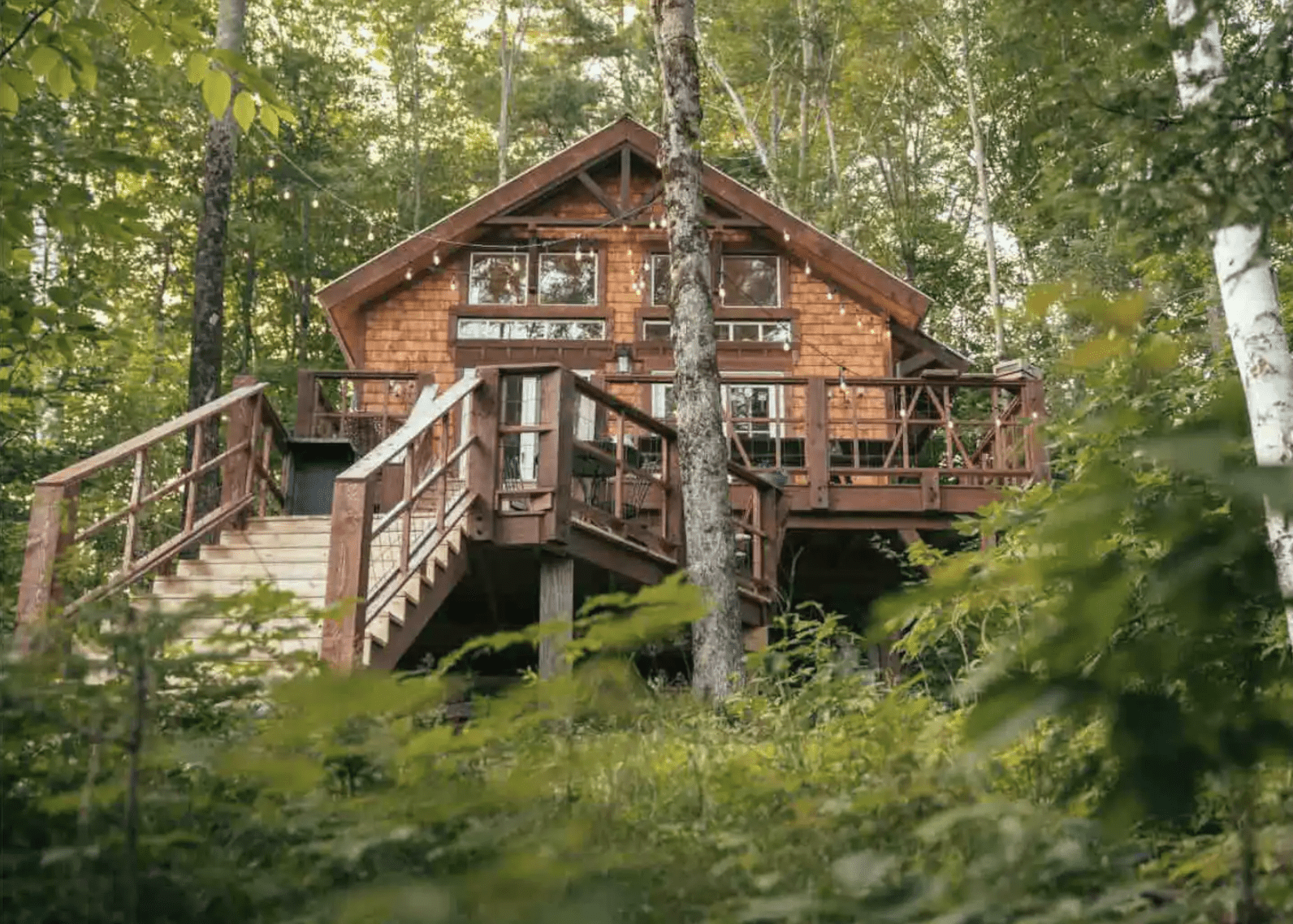 Wooden treehouse surrounded by the woods with a large walk up staircase.