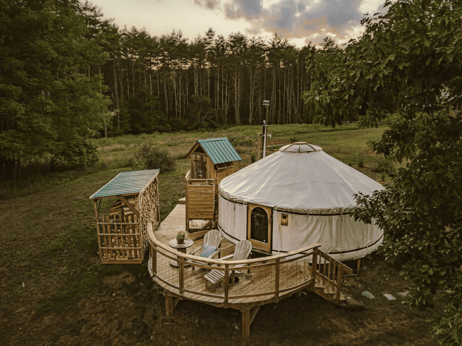 White yurt surrounded by woods on a cloudy night.