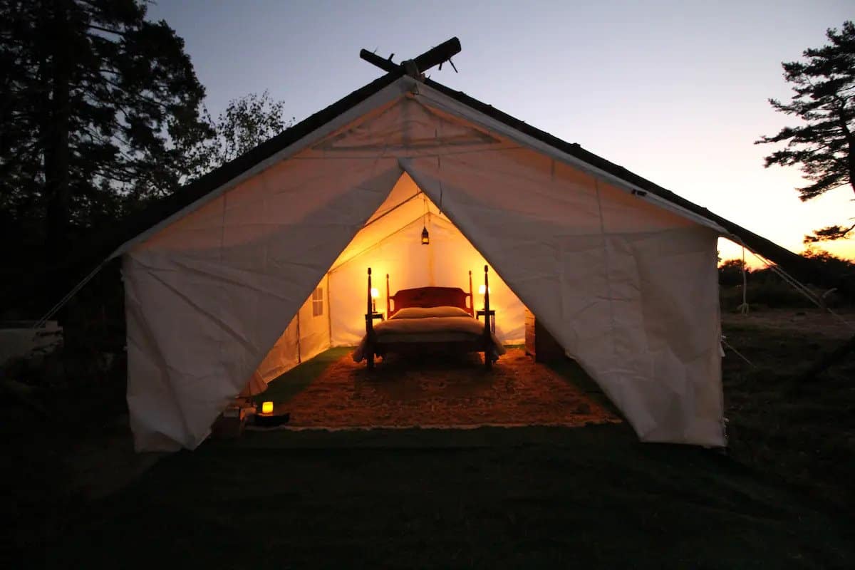 Open tent with warm lighting under a dark blue sky