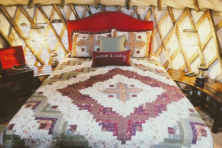 Red comforter on a bed inside of a yurt