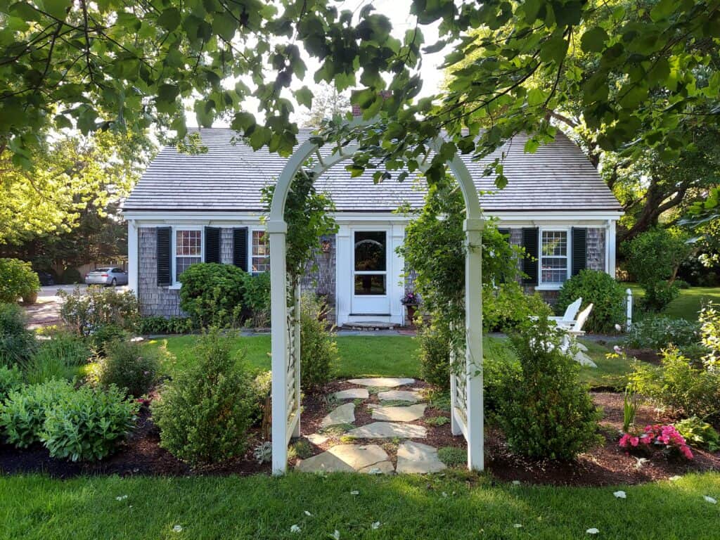 A quaint Cape Cod inn is seen with lush landscaping