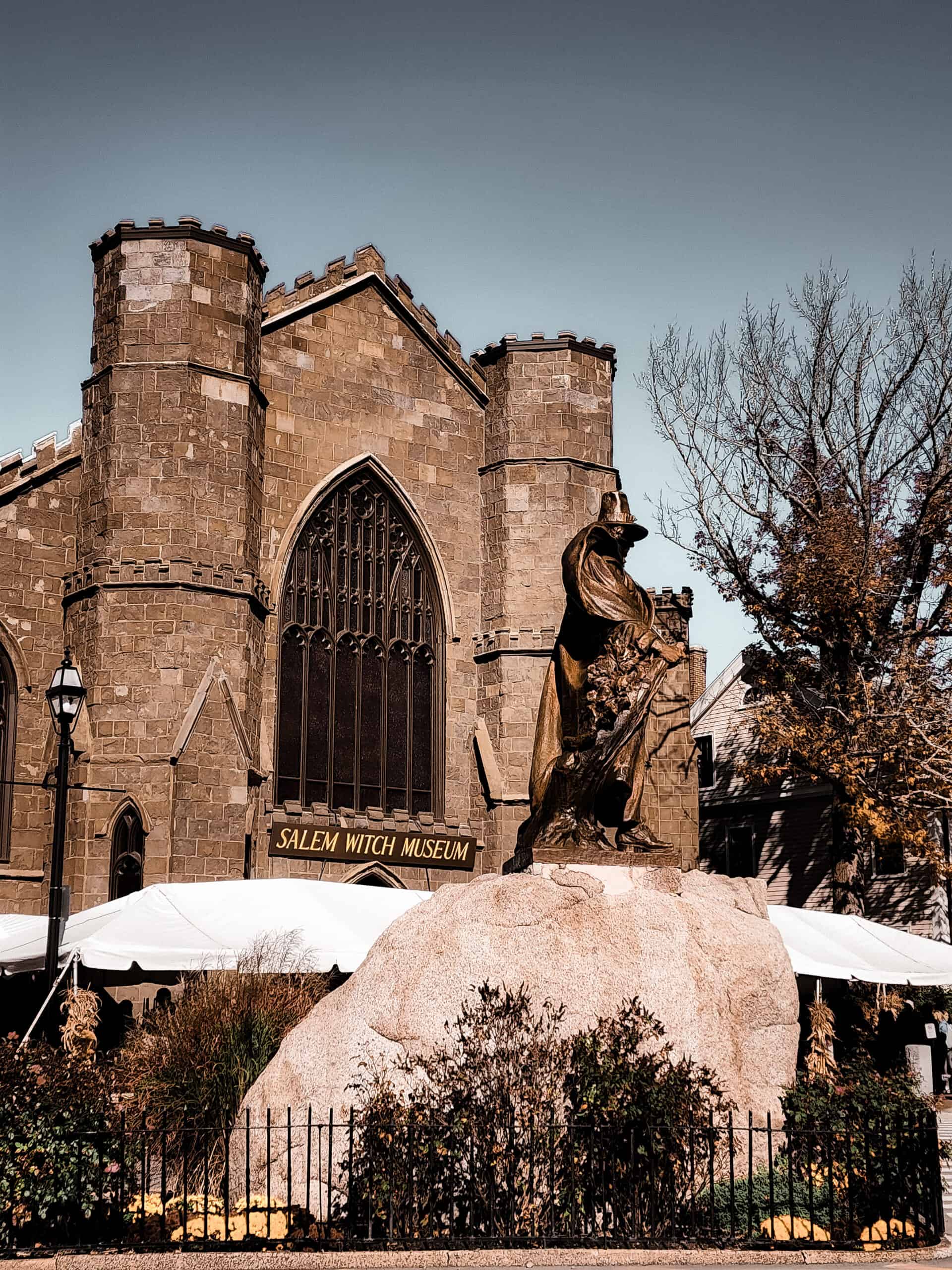 exterior of the Salem Witch Museum seen from a distance with a Puritan statue in the foreground