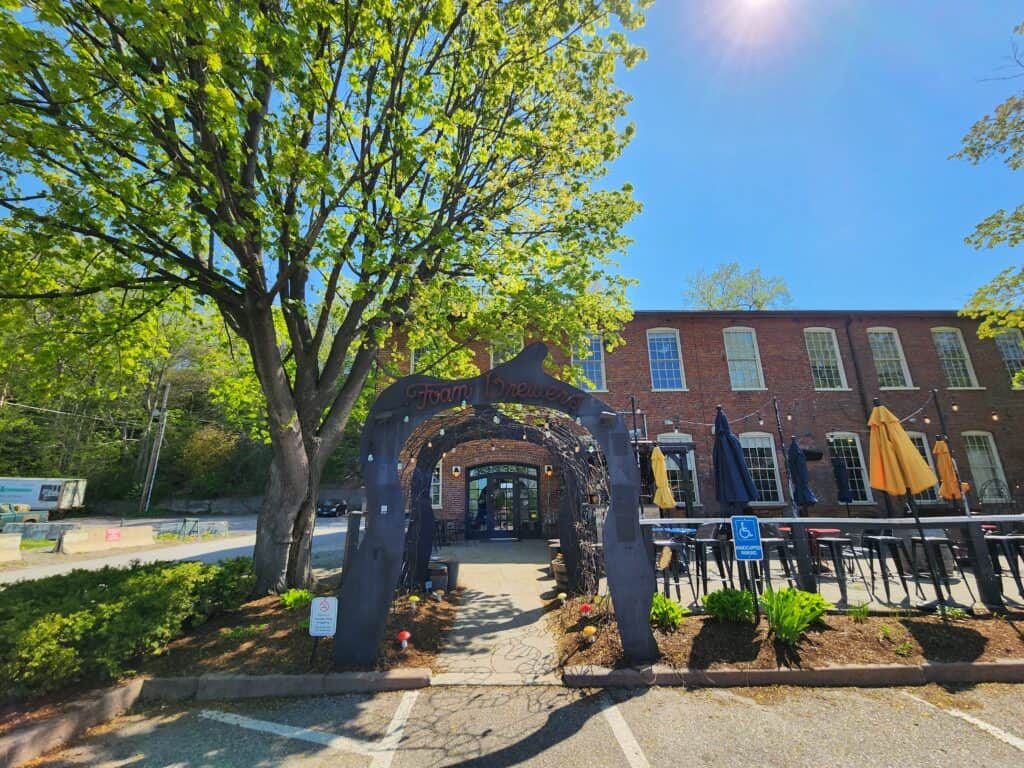 exterior of a brewery restaurant on a sunny summer day. Wrought iron sign reads Foam Brewers