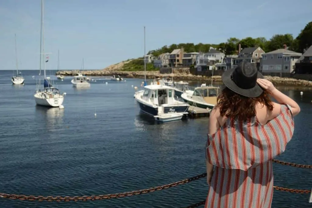A woman stands with her back to the camera, facing the sea in Rockport, Massachusetts