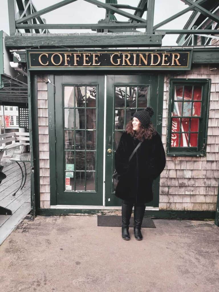 A woman stands in front of a coffee shop in Newport, Rhode Island, dressed for winter.