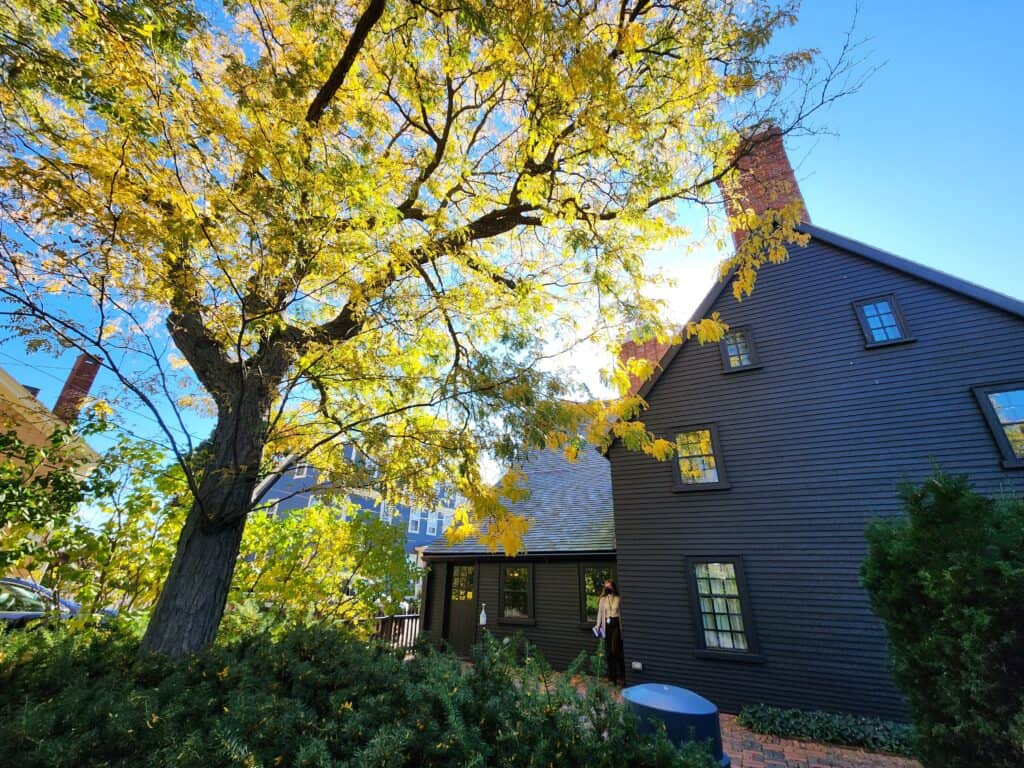 exterir of a dark colonial type house with a yellow fall tree to the side - the House of the Seven Gables Salem MA