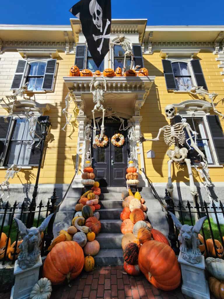 a house elaborately decorated for halloween, with skeletons attached to window frames, pumpkins everywhere and more
