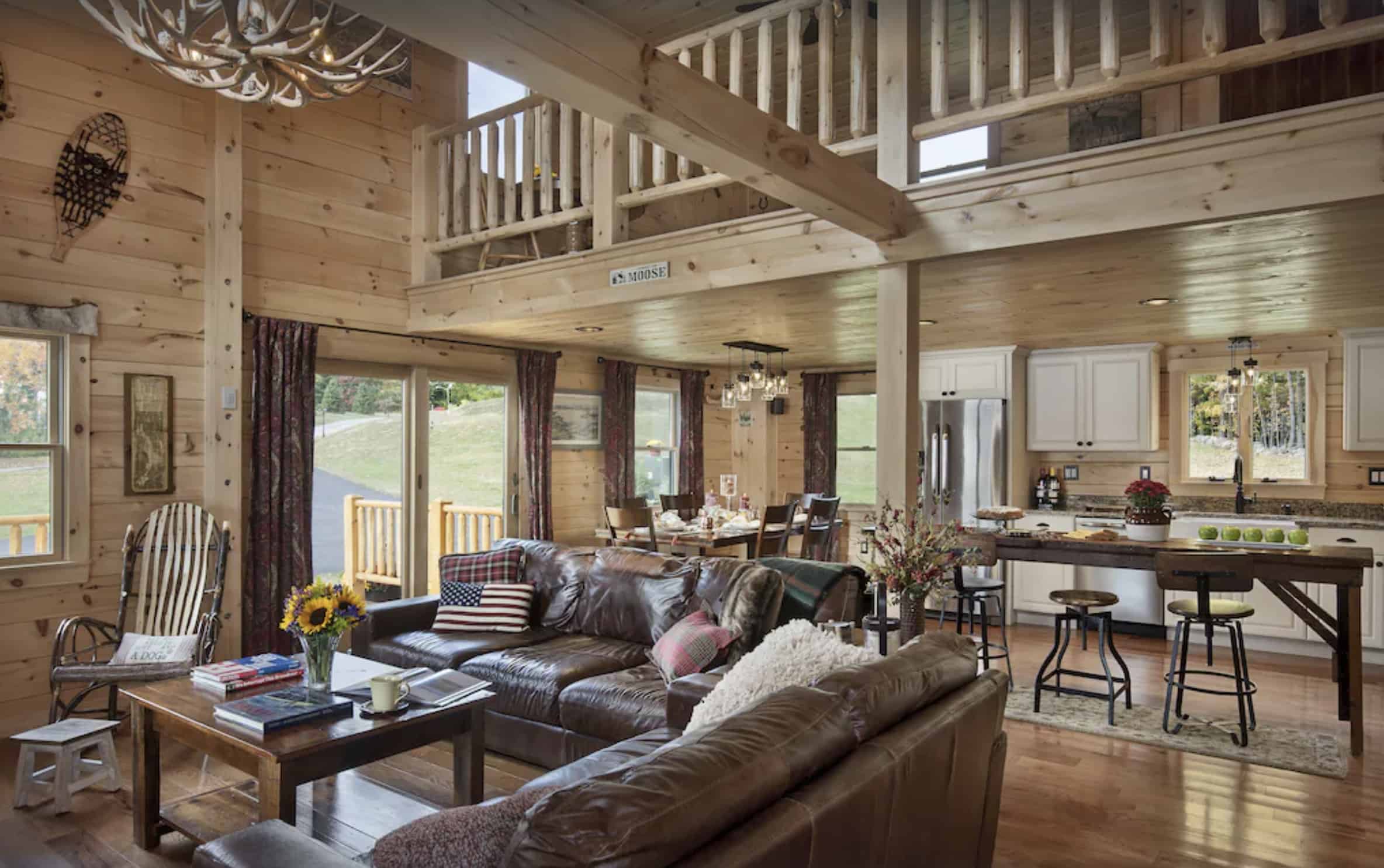 Living room inside of a wooden cabin with a leather couch and high, vaulted ceilings.