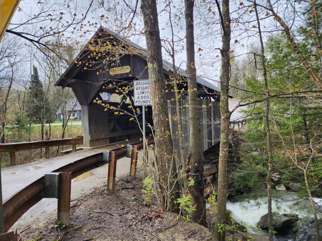 a classic wooden covered bridge in vermont, sits over a rushing river. Emily's Bridge Stowe Vermont