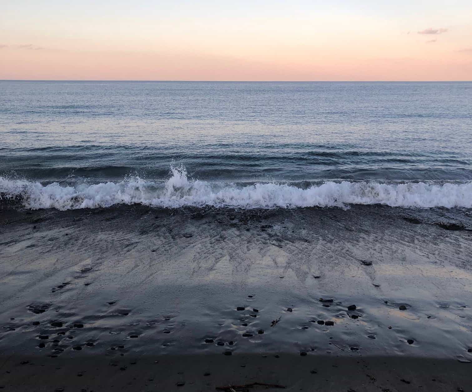 Waves crashing against the sand at sunset