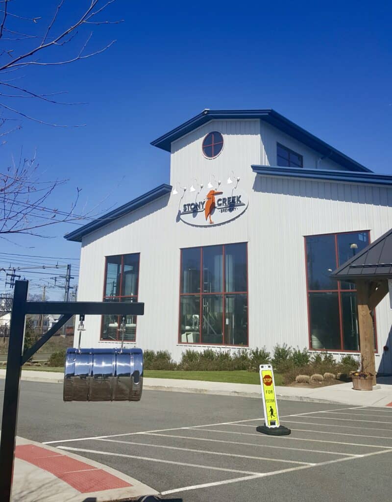 The exterior of one of the top Connecticut breweries on a sunny day with large windows where you can see the brewing facility inside