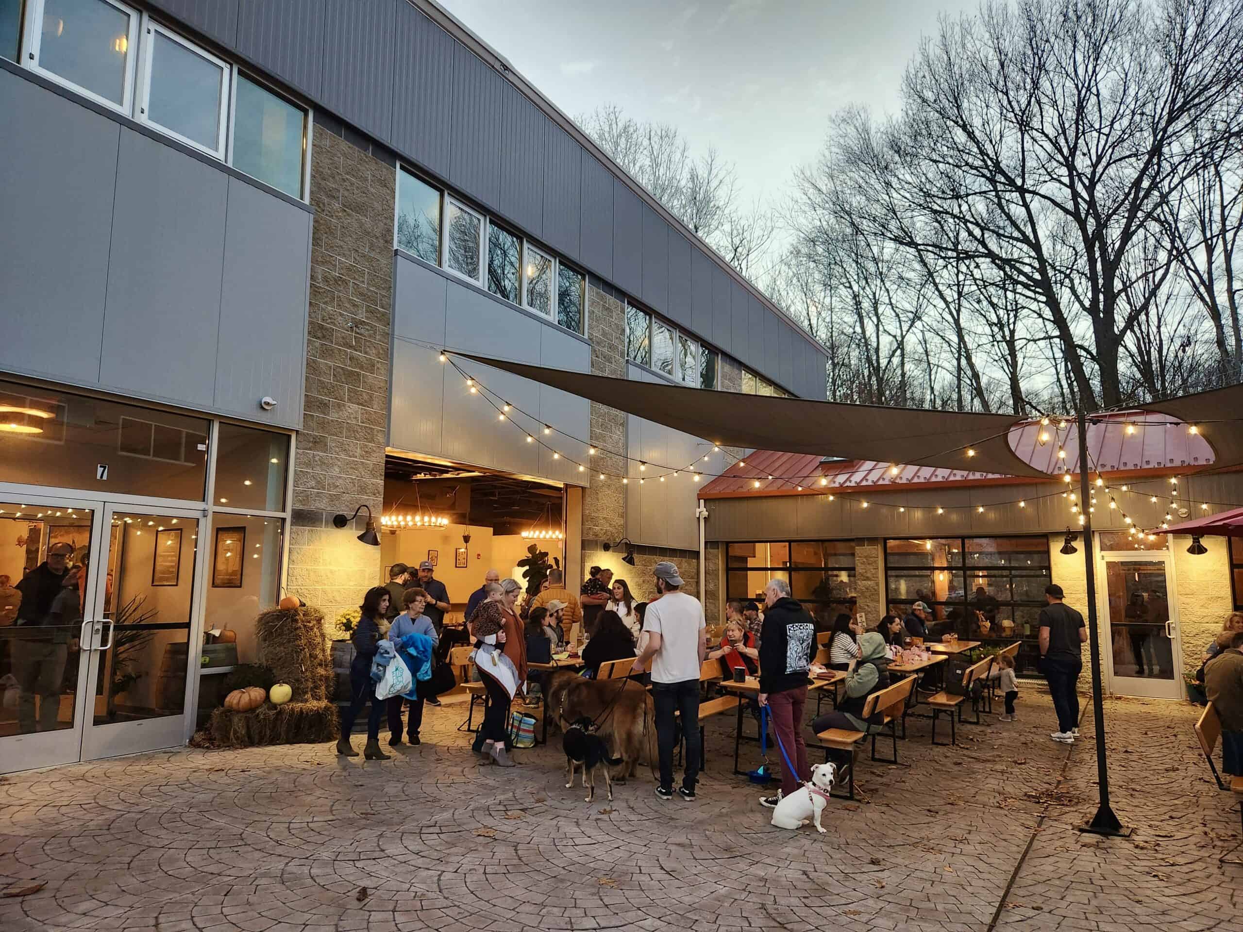 Outdoor seating with people sitting under a lit canopy at one of the most popular Connecticut breweries