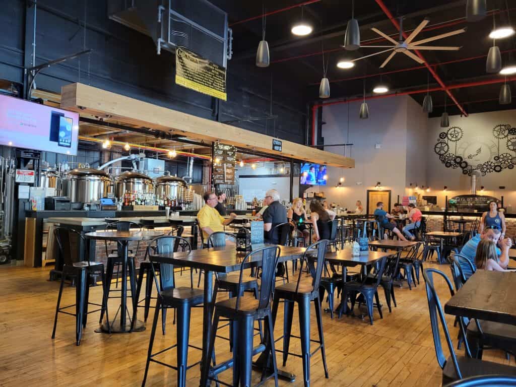 The inside of a brewery in Connecticut with people sitting at tall industrial style tables