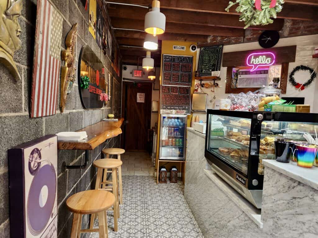 A quaint New Haven coffee shop has a long, narrow counter for sitting opposite of the display case