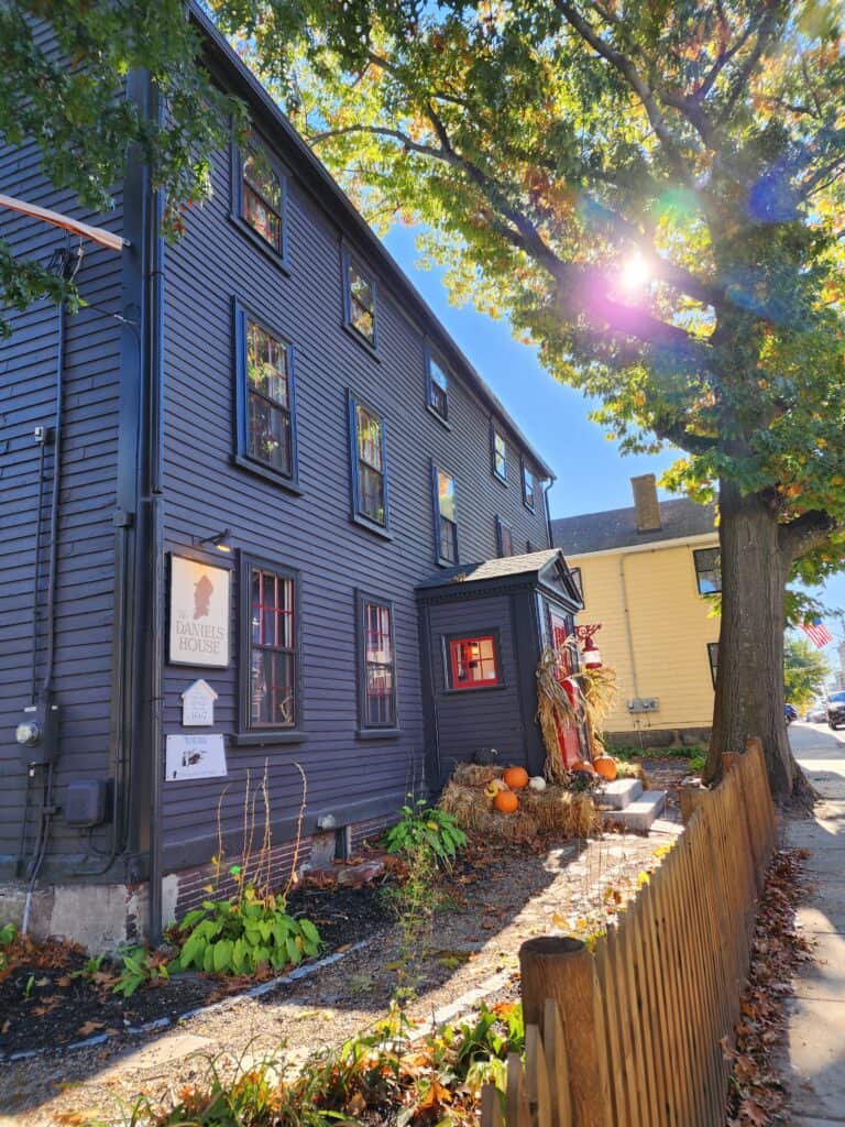 A dark blue bed and breakfast in Salem, Massachusetts during the fall season with pumpkins and hay around the front door