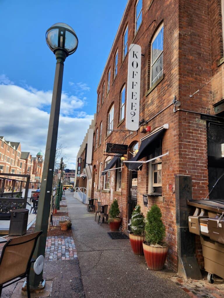 A New Haven street is pictured with a sign for a popular coffee shop hung on a brick building