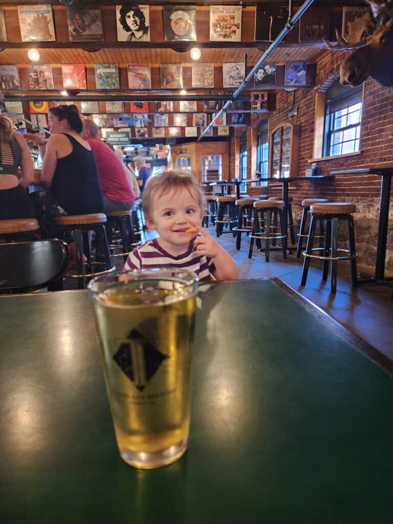 a smiling toddler sitting inside a pub/restaurant