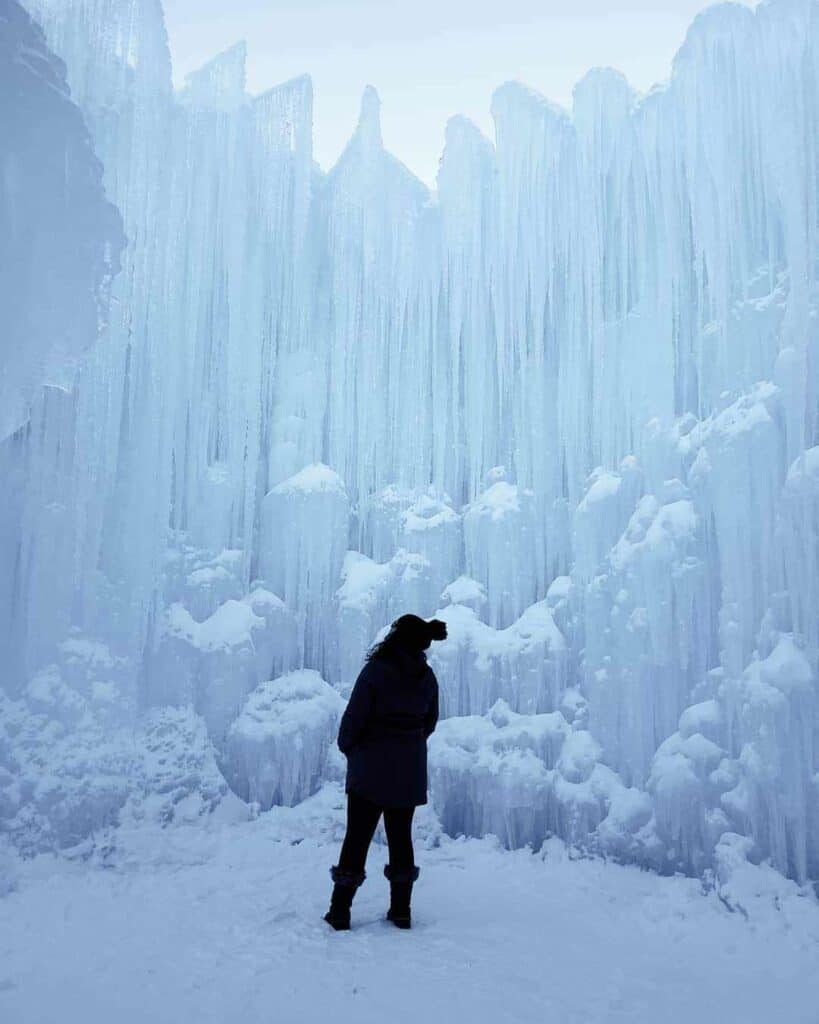 A woman stands looking up in awe at the New Hampshire ice castle