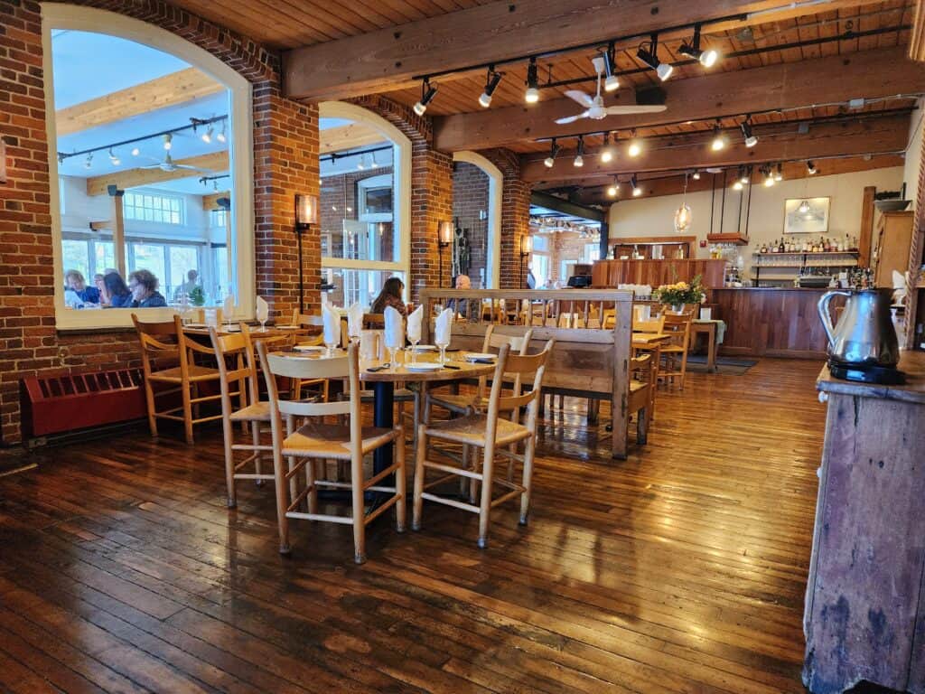 an inviting interior of a restaurant in quechee vermont. wooden tables, a shiny wooden floor, and cozy lights