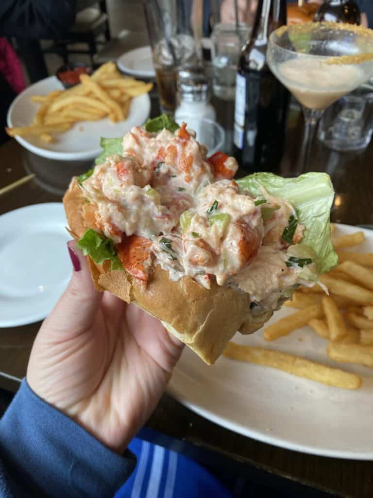 A hand holding a lobster roll at Coast Guard House in Narragansett, RI