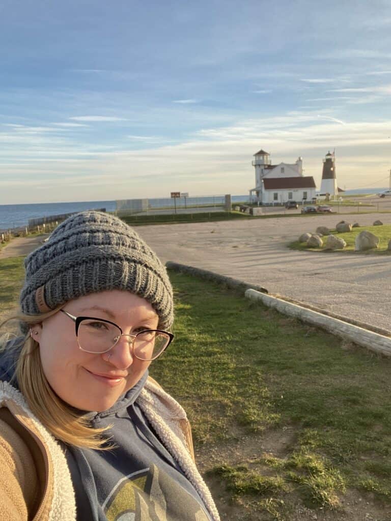 A woman smiling in front of Point Judith Lighthouse in Narragansett, Rhode Island