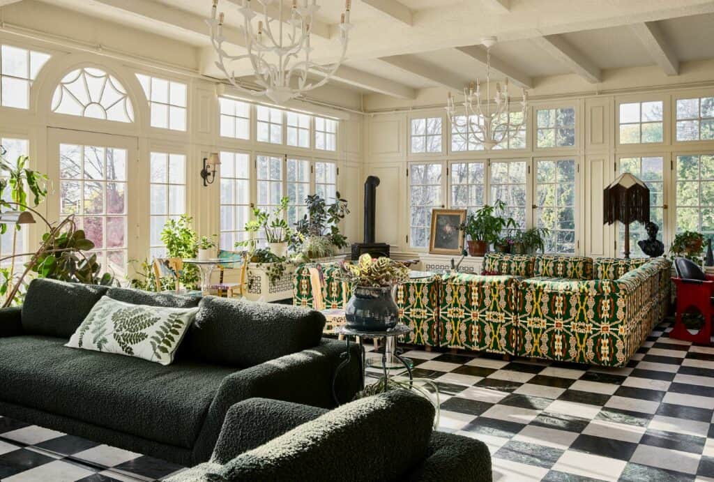 A beautiful sun soaked room with black and white checkered floors and comfortable looking furniture