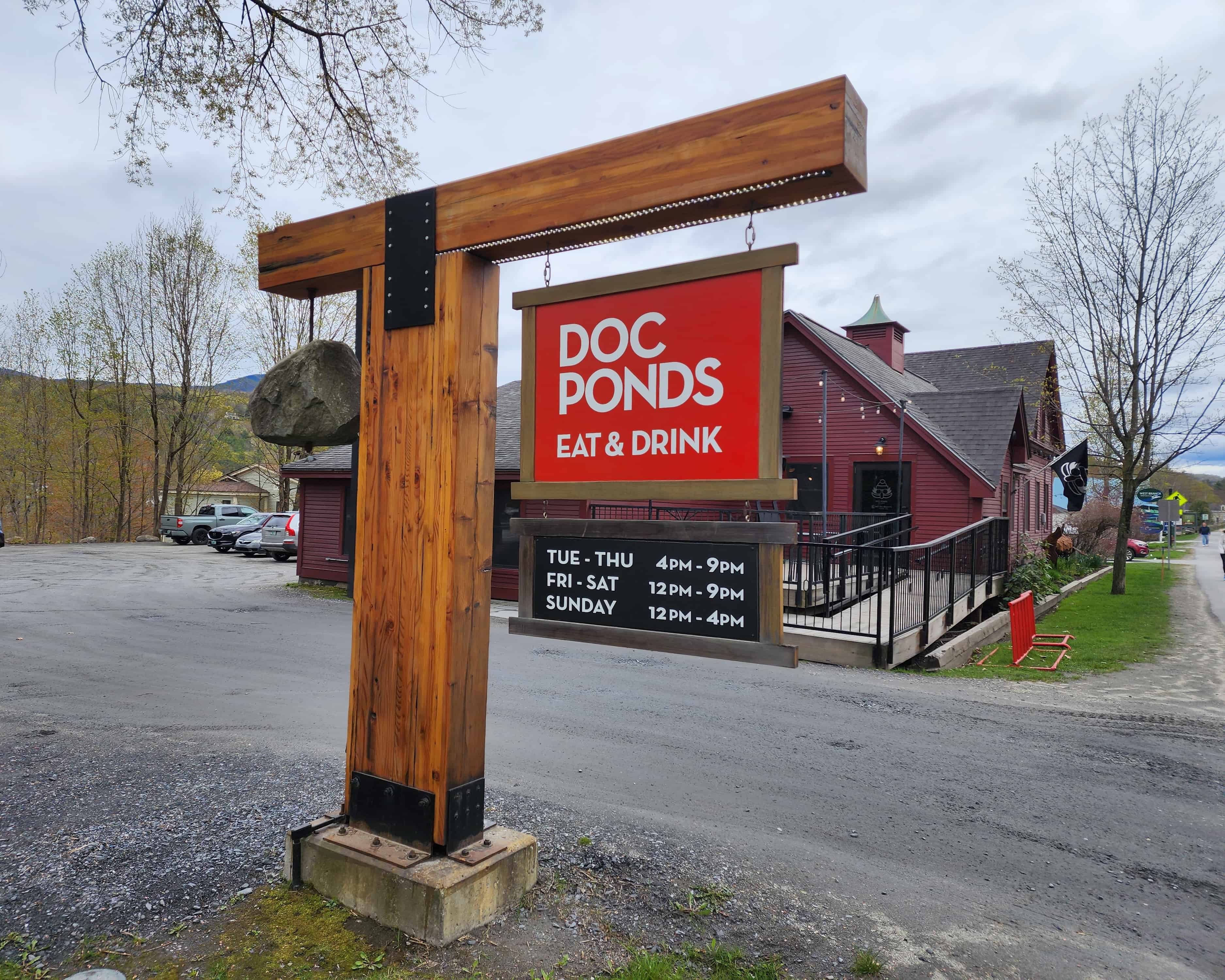 exterior of a restaurant a plain red building is set behind a bright red sign that reads Doc Ponds Eat & Drink
