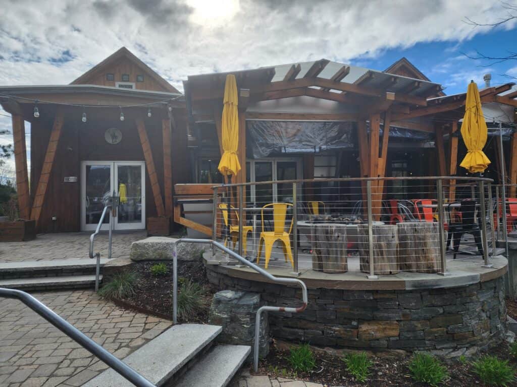 an empty outdoor restaurant patio awaiting guests. yellow table umbrellas are closed and seats are empty