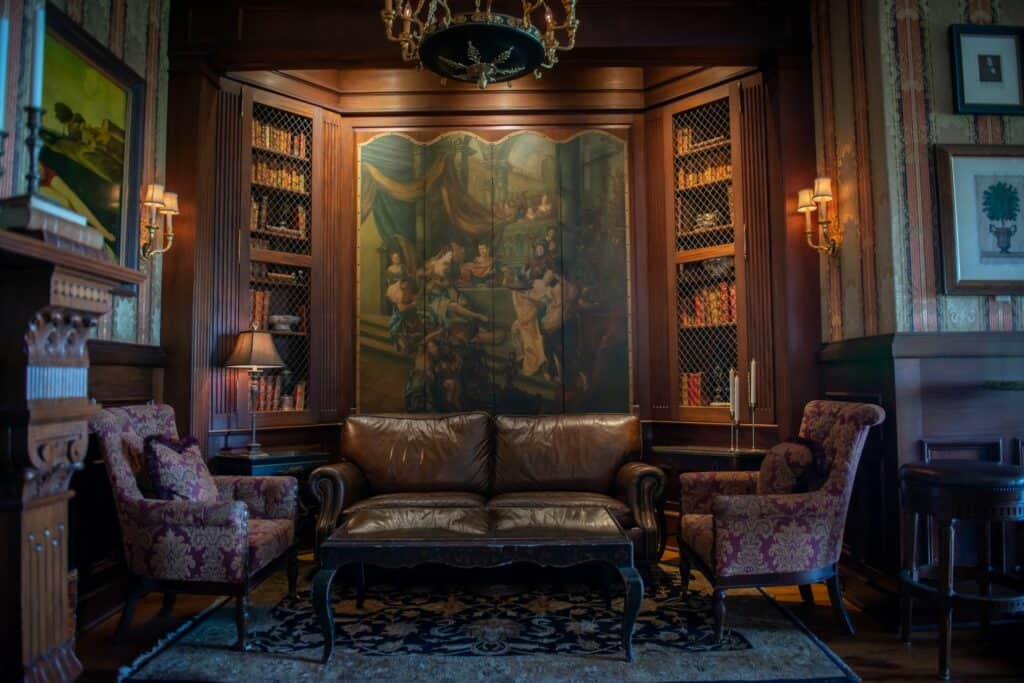 A dramatic and moody bar corner with plush leather couches and dark wood with fine art on the walls 