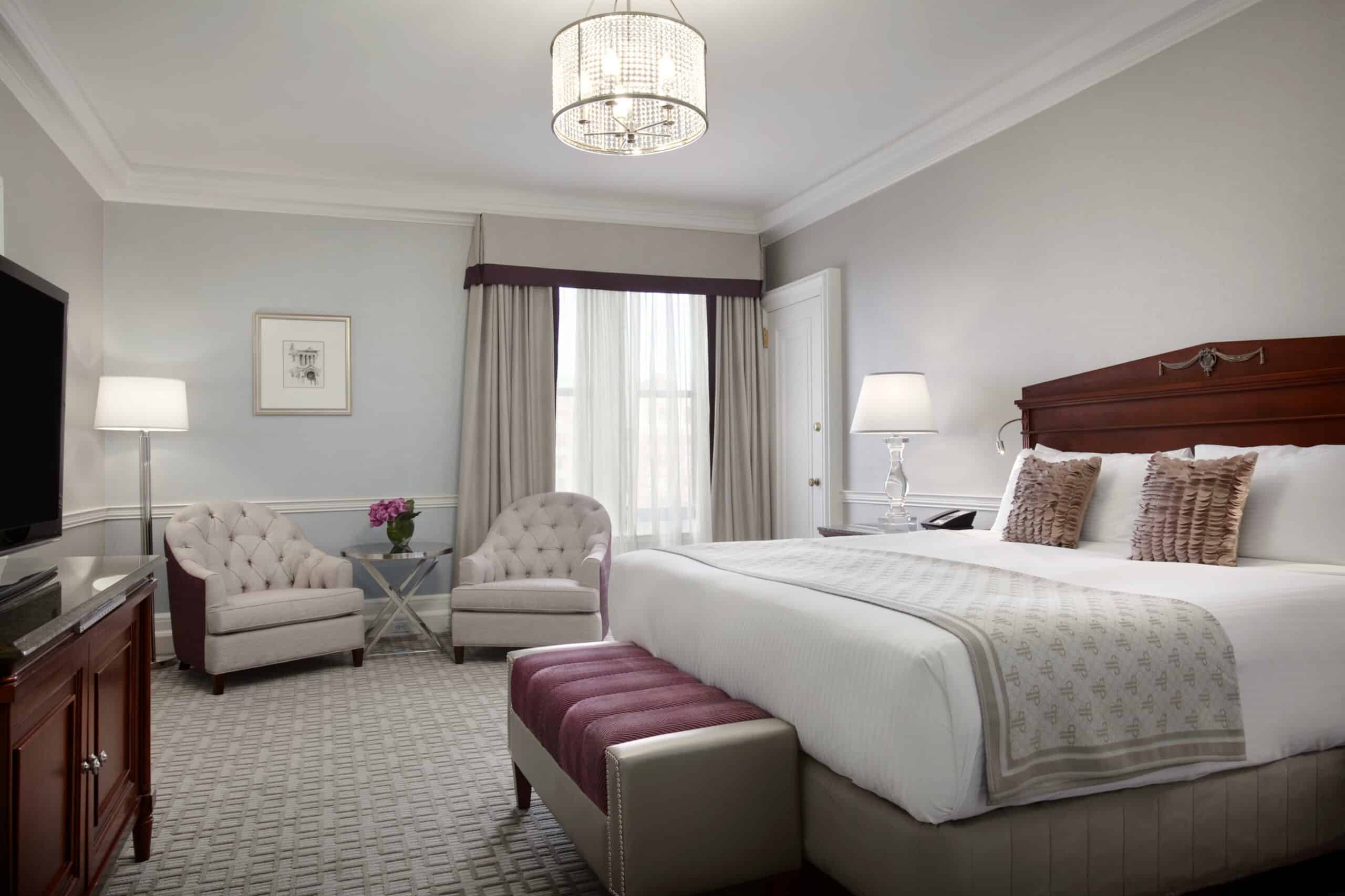 White plush bed in a hotel room with a seating area.