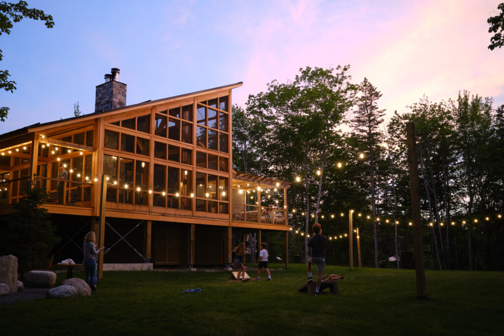 The exterior of Terramor Outdoor Resort is seen with lights strung around a deep green lawn at dusk