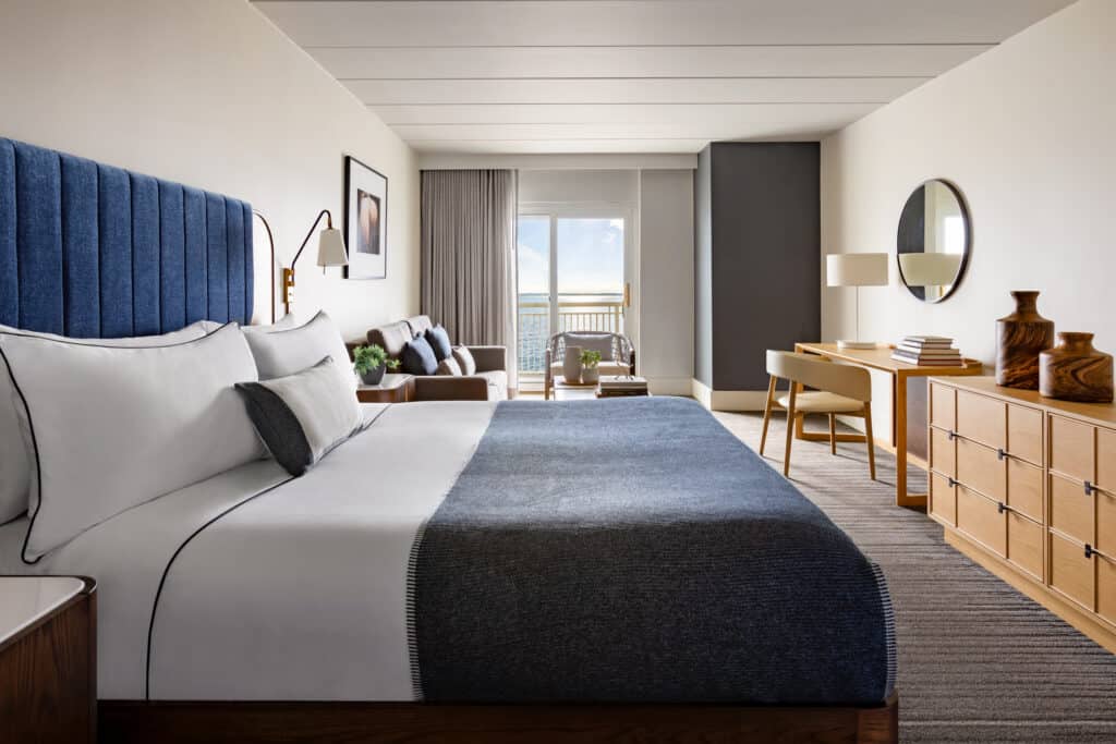 A hotel room at a popular Newport, Rhode Island resort is seen with a King sized bed and water views beyond.