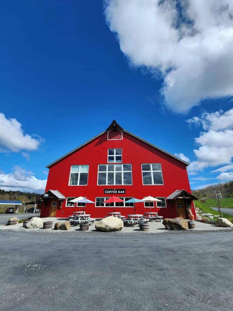 a gorgeous blue sky is seen behind a vibrant red barn-type building bearing a sign that reads coffee bar