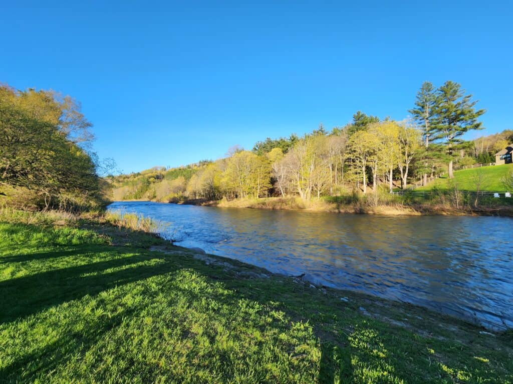 a wide calm river fringed by spring and summer green, vermont