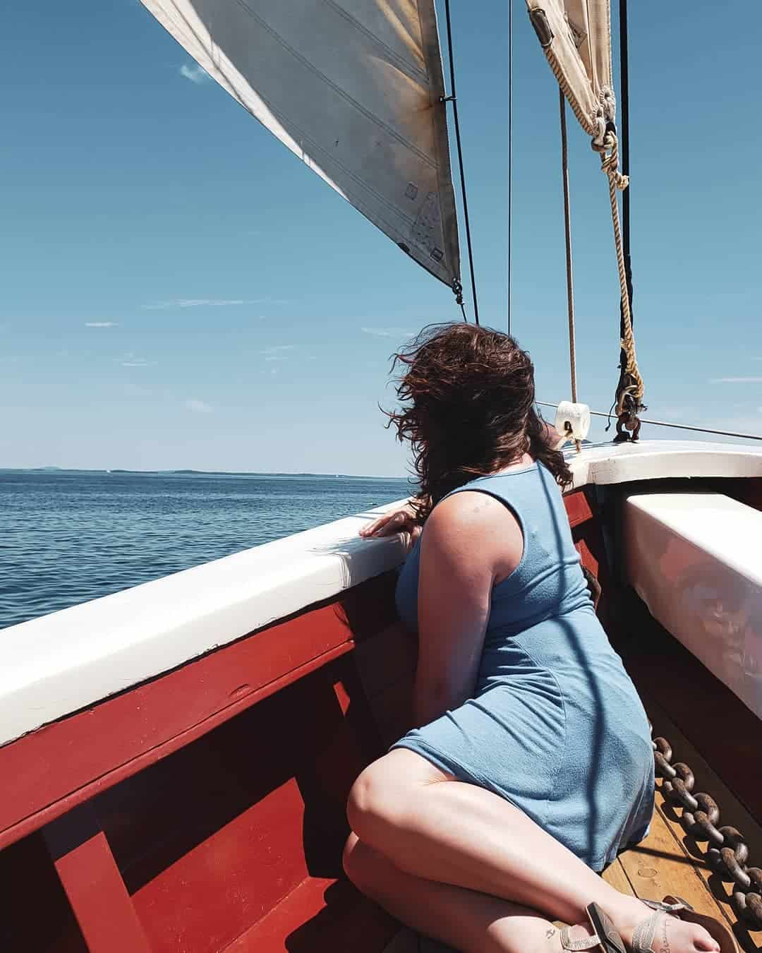 amy sitting in the front of a classic sail boat, maine coast