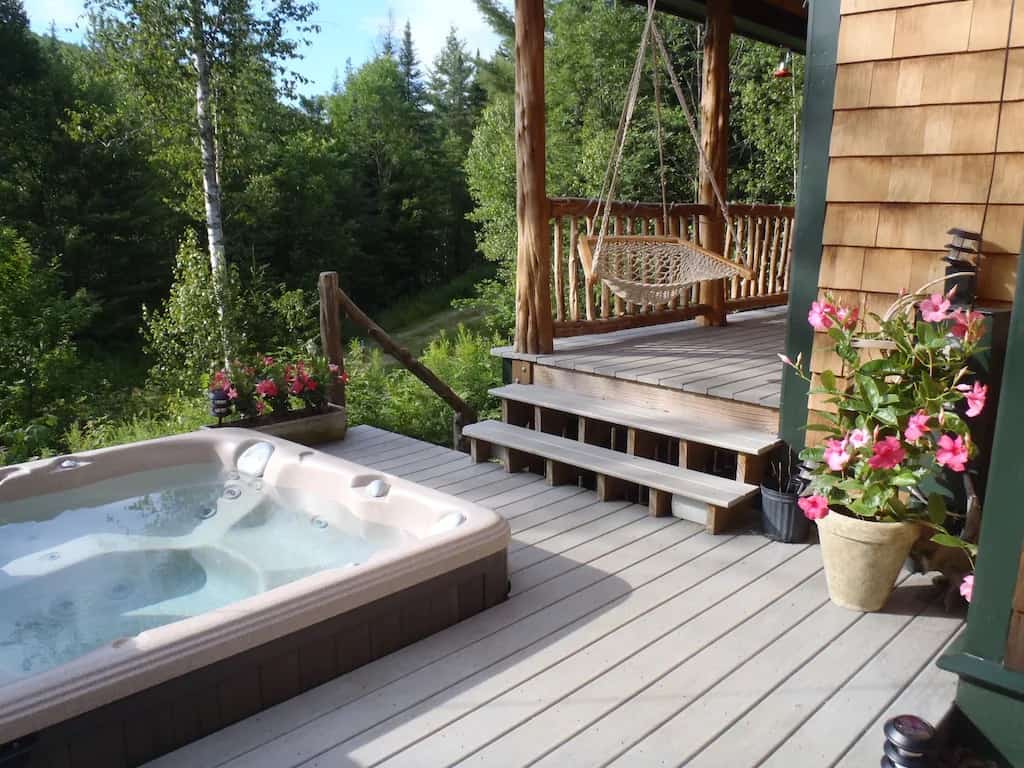 Hot tub embedded in a deck with a forest behind.