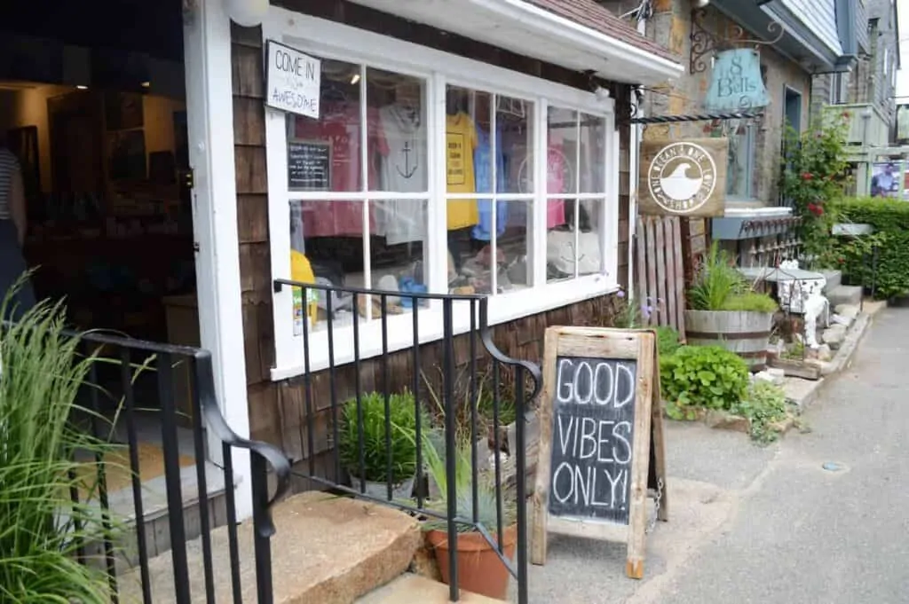 A store front with colorful shirts on display and a sign saying "Good Vibes Only" out front