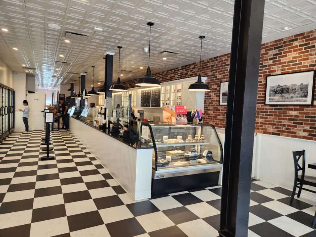 An ice cream shop with a long service counter, exposed brick wall, and black and white checked flooring