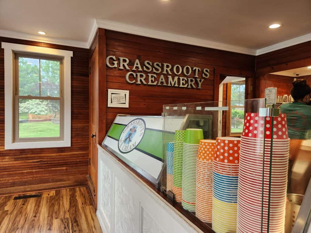A long ice cream counter with colorful paper cups in a wood paneled ice cream shop in Connecticut