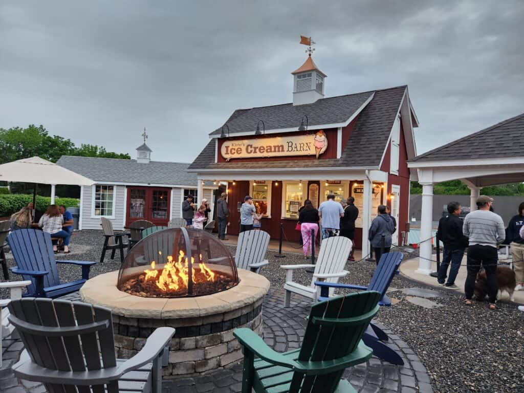 An outdoor line formed at a popular ice cream shop in Connecticut with a seating area in the foreground
