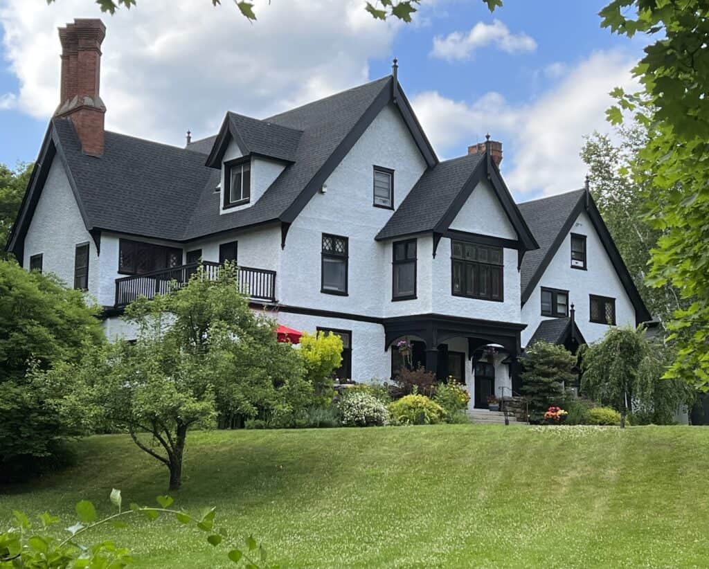 The outside of a large Manor House bed and breakfast in Connecticut with a lush, green yard