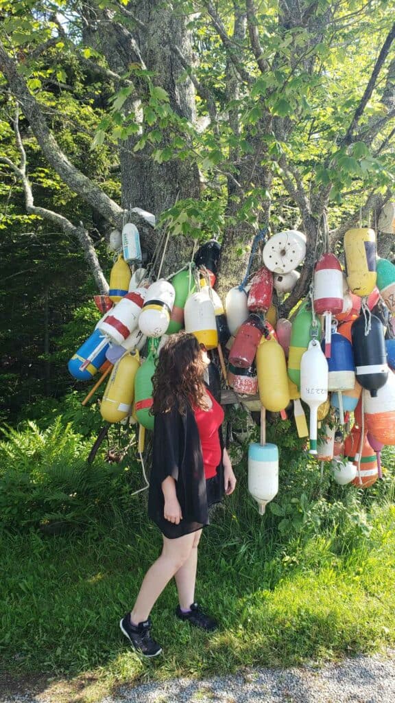 A woman looks up at colorful buoys in Deer Isle, Maine