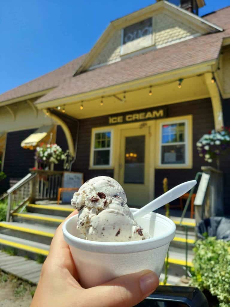 A hand holding up ice cream in front of an ice cream place in Cape Cod