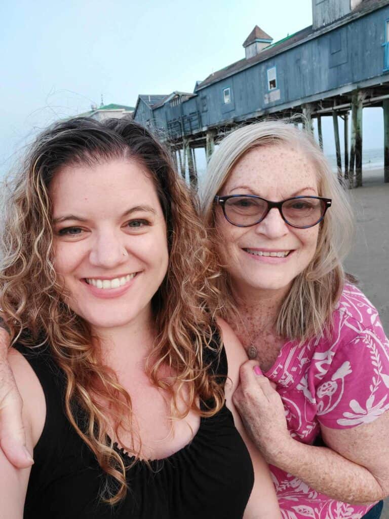 Two women pose in front of the Old Orchard Beach Pier