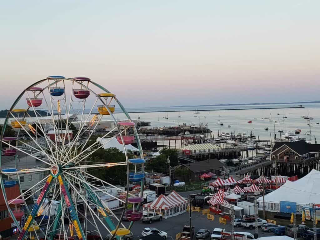 A seaside Maine beach town with a ferris wheel and boats in the distance