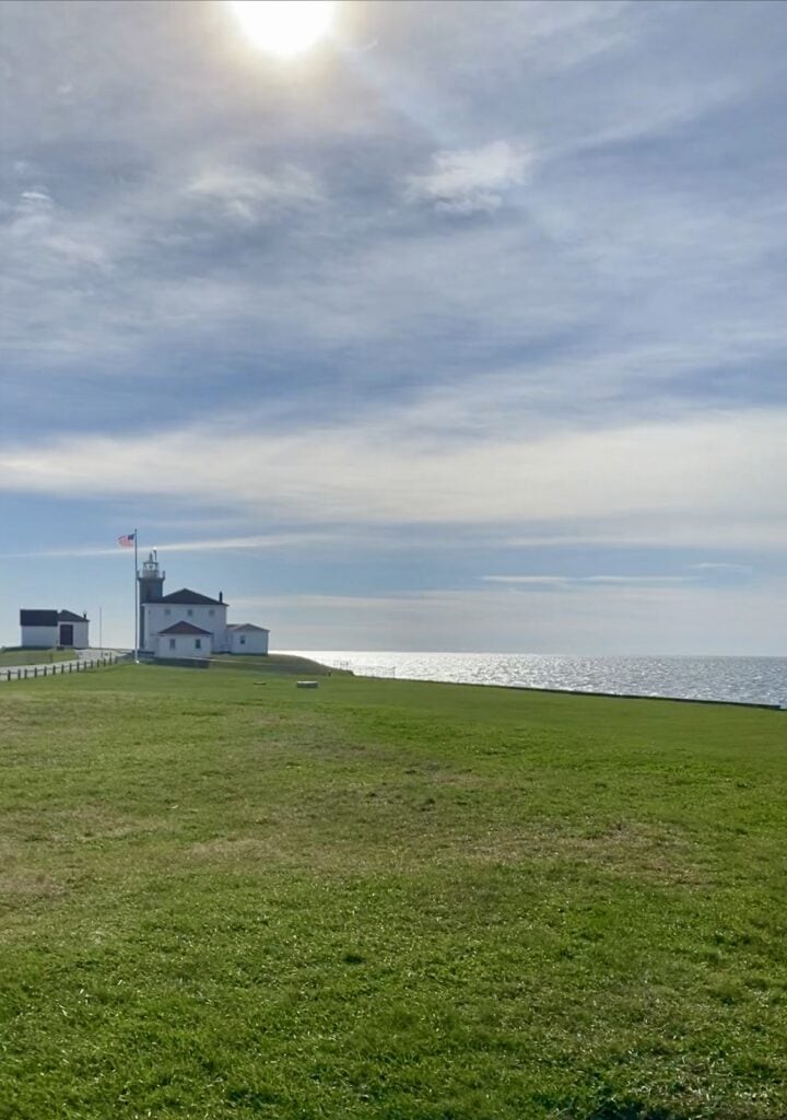 The Watch Hill Lighthouse in Westerly Rhode Island on a sunny day surrounded by green grass